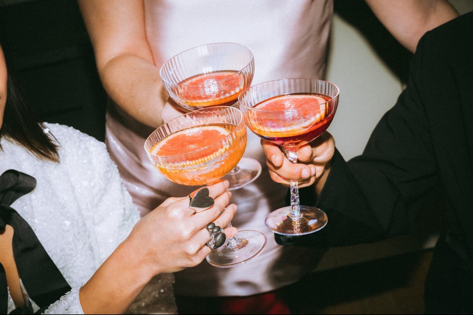 Wedding guests toasting with grapefruit cocktails in coupe glasses at an adults-only celebration